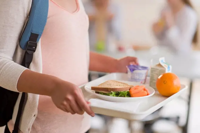 Female student carrying tray in cafeteria