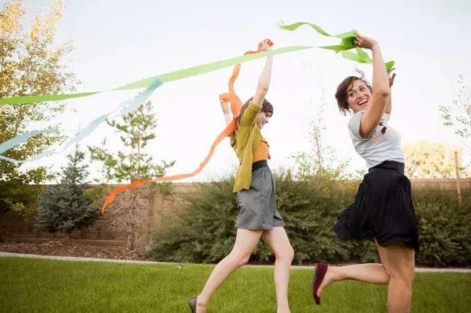 Two happy female friends playing in domestic garden