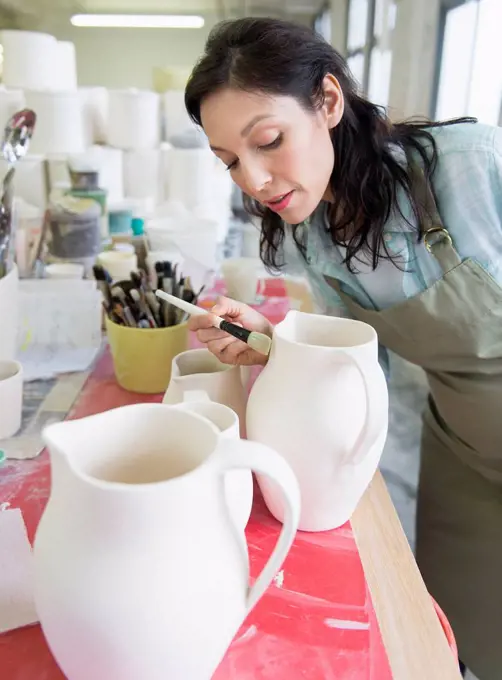 Female artist decorating pottery in studio