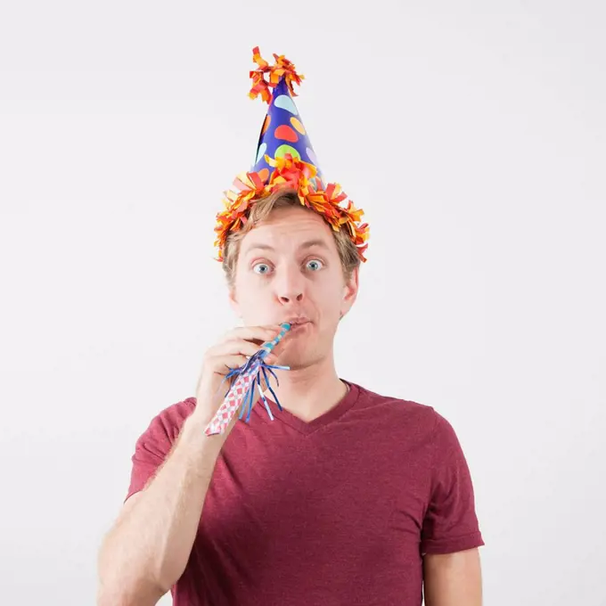 Man with party hat and party horn blower