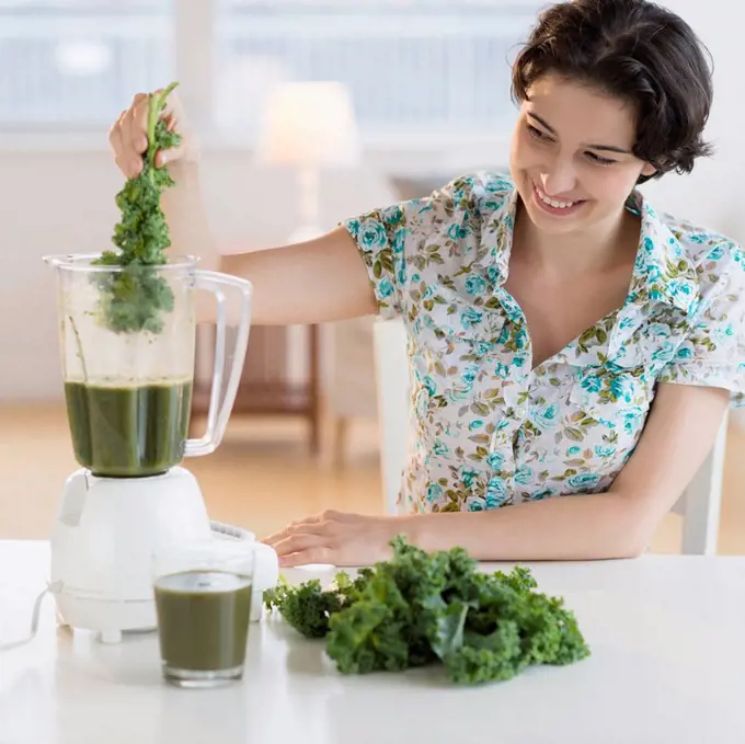 Woman preparing healthy drink with kale