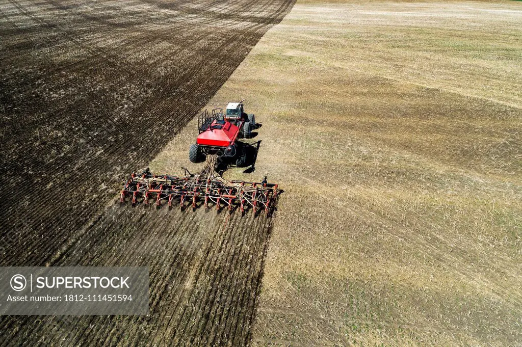 Aerial view to a Tractor with sowing machine working on a field