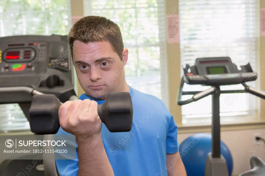 Man with Down Syndrome exercising in a gym with dumbbell