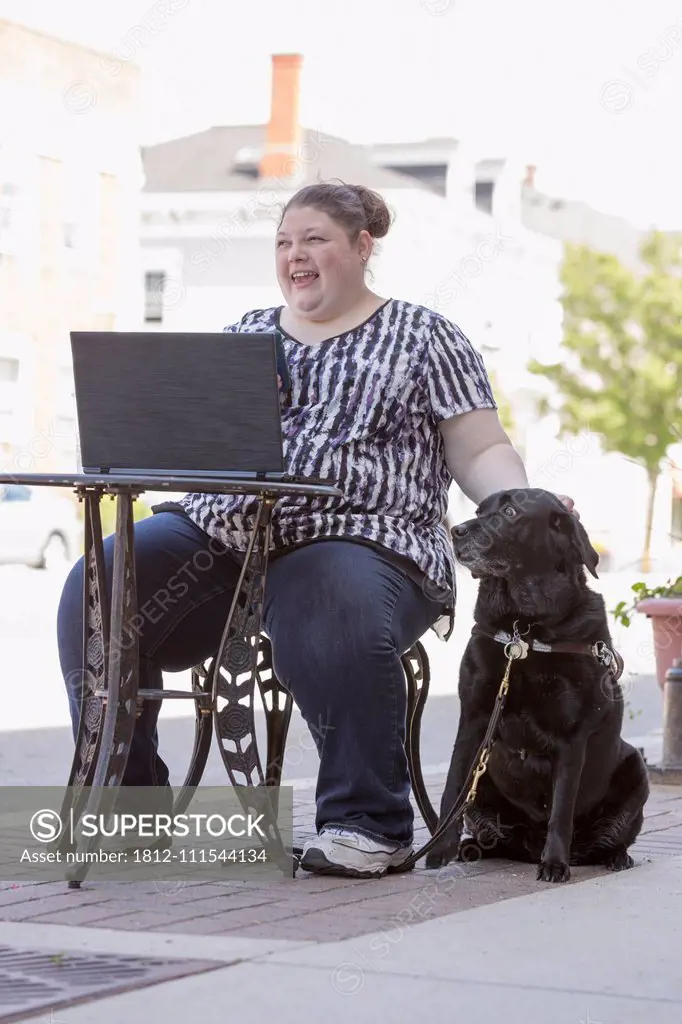 Woman with Visual Impairment sitting at a café with her computer and service dog