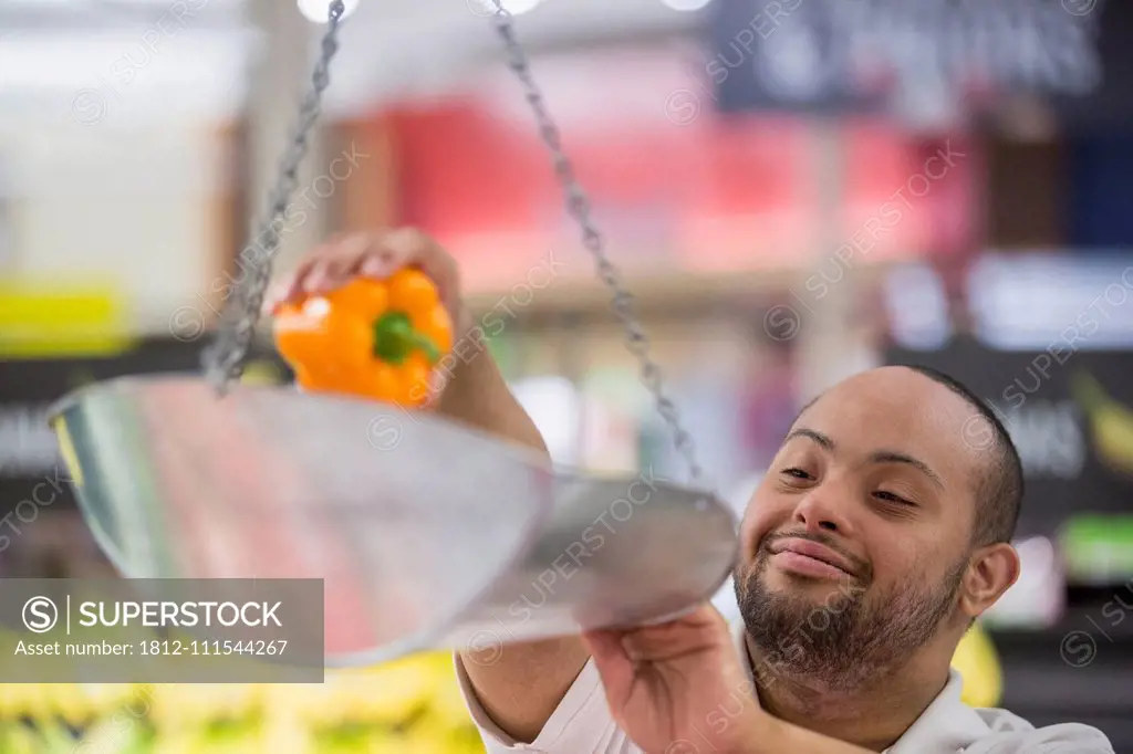 Man with Down Syndrome weighing vegetables in a grocery store