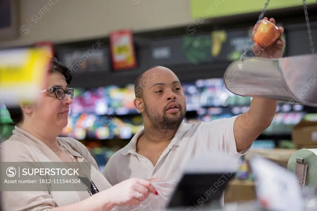 Man with Down Syndrome weighing fruit in a grocery store