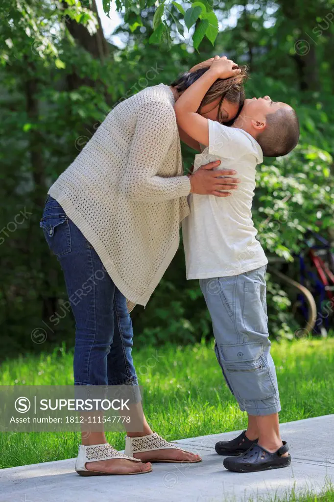 Hispanic boy with Autism hugging his mother in park