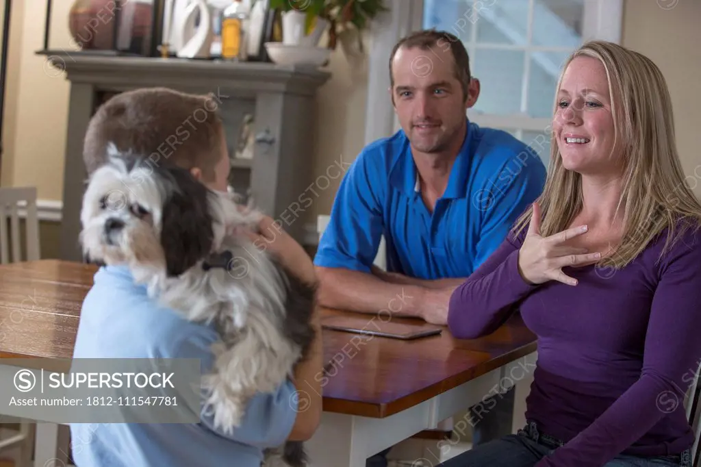 Parents communicating with son in American Sign Language about 'Feeling' at home