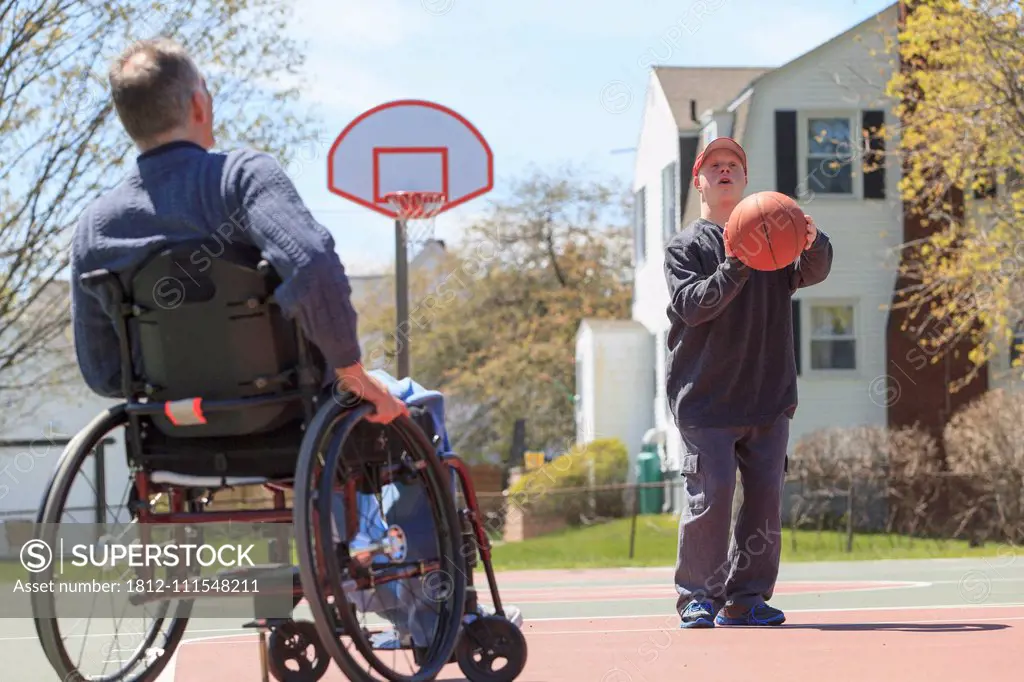 Father with Spinal Cord Injury and his son with Down Syndrome playing basketball in a park