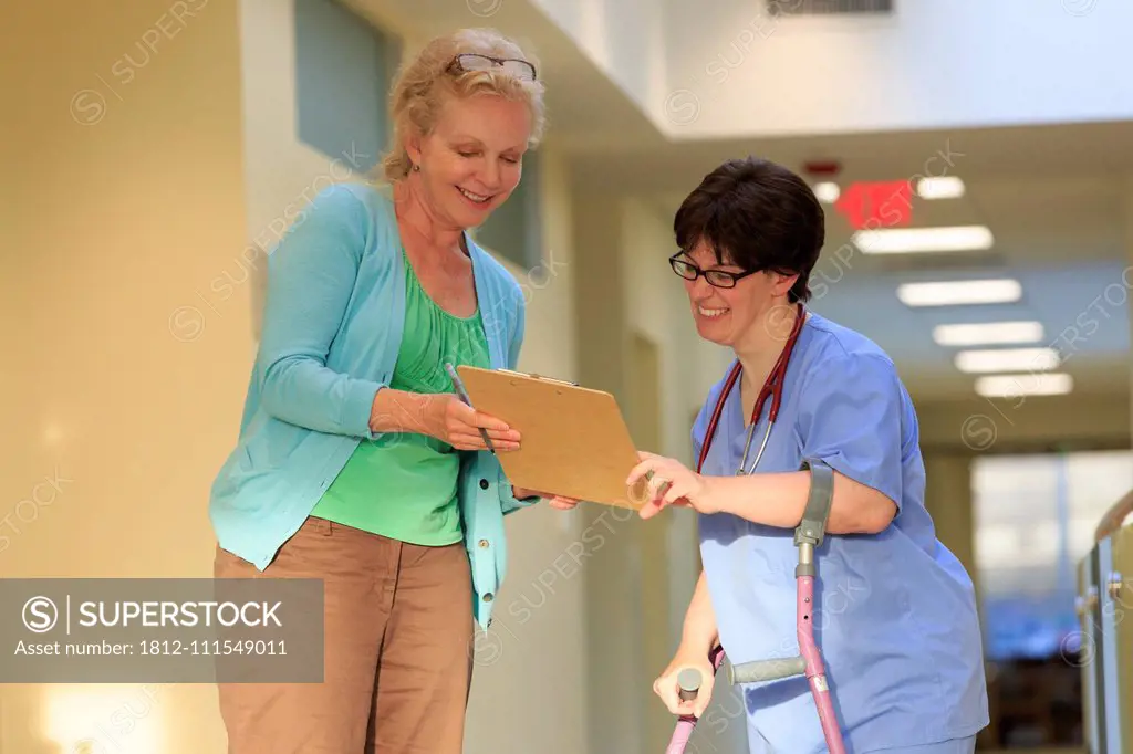 Nurse with Cerebral Palsy on canes looking at patient records