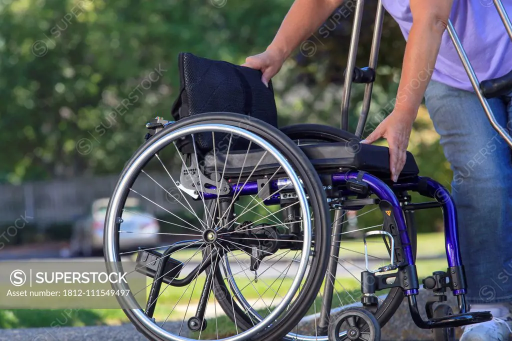 Woman with Spina Bifida using crutches to put wheelchair together after traveling in the car