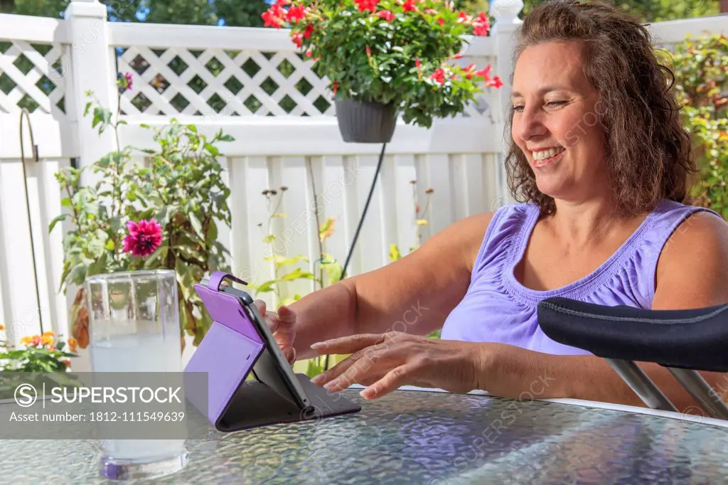 Woman with Spina Bifida on patio working on tablet