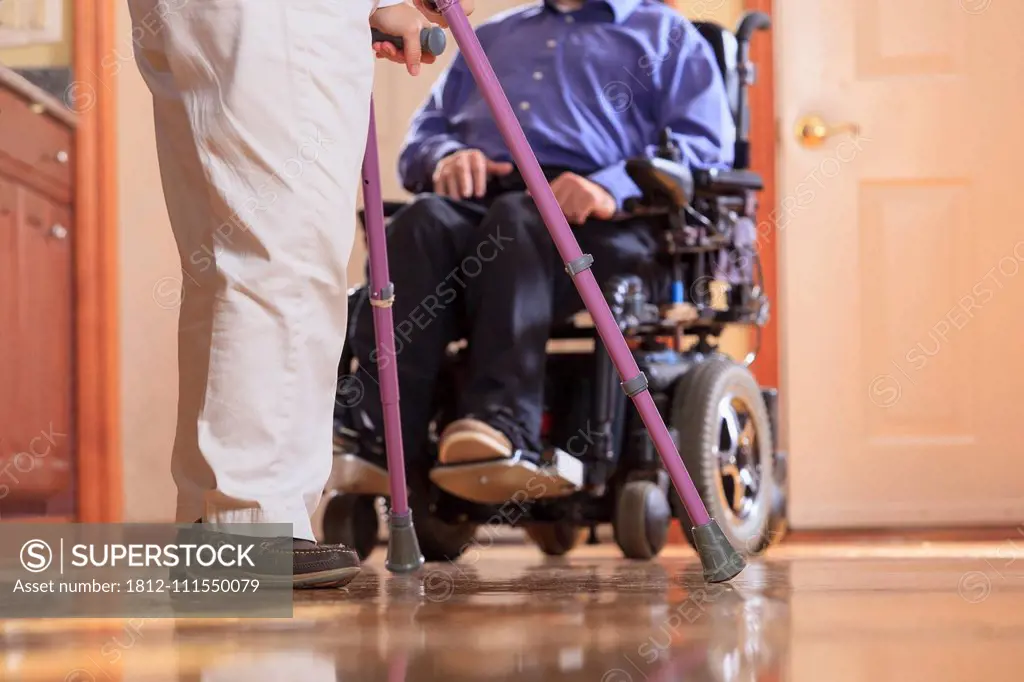 Woman with Cerebral Palsy using crutches and her husband with Cerebral Palsy in a motorized wheelchair