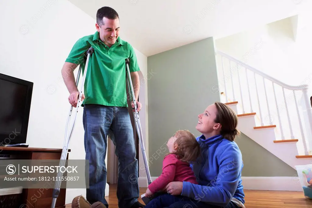 Man after anterior cruciate ligament (ACL) surgery with wife and daughter at home