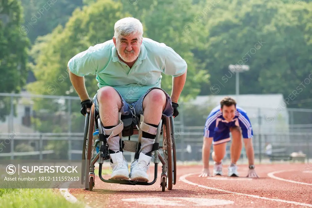 Young man racing with a senior man with Muscular Dystrophy on a racetrack.