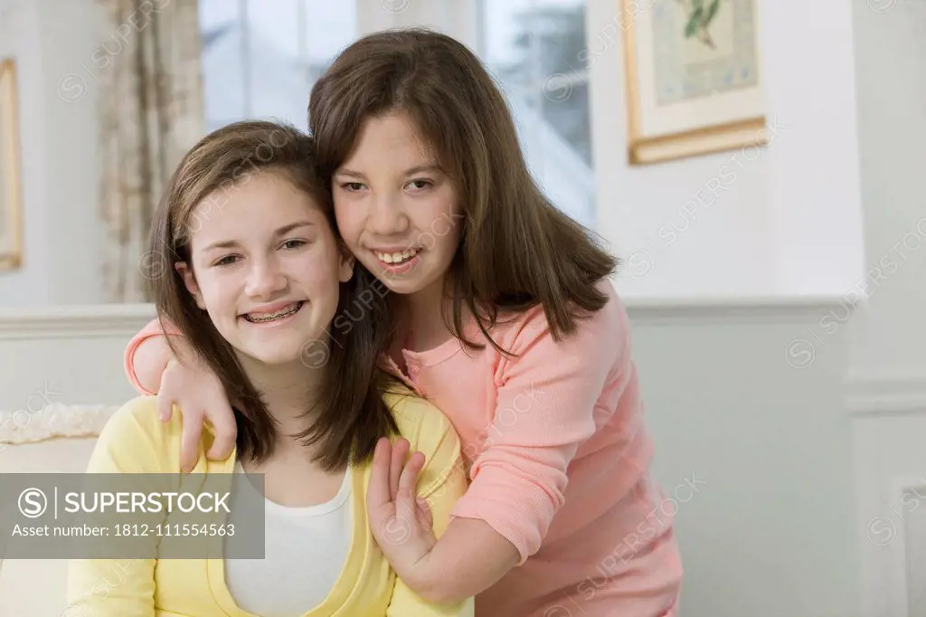 Two teenage girls smiling together, one with birth defect