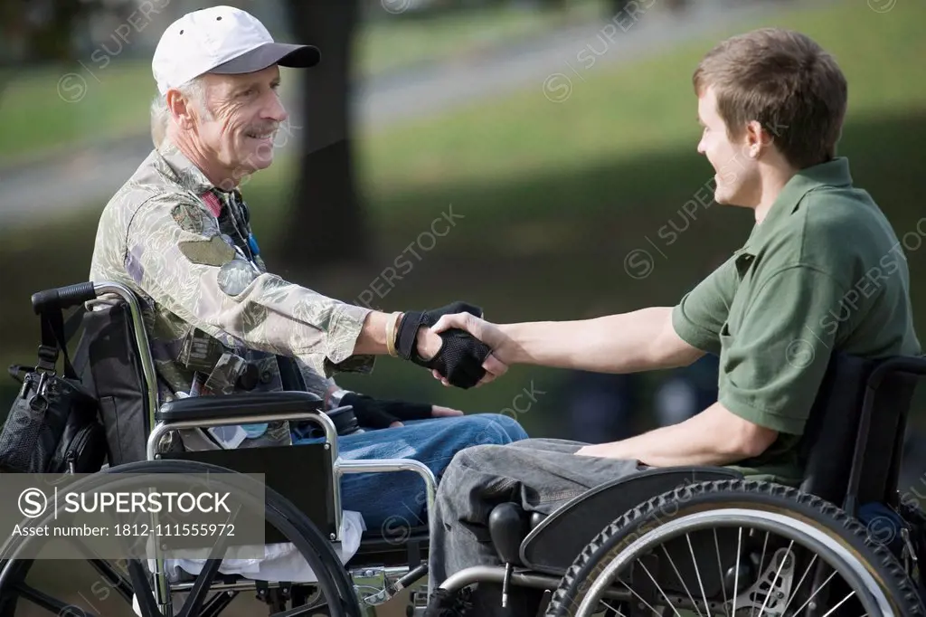 Side profile of a mature war veteran shaking hands with a young man