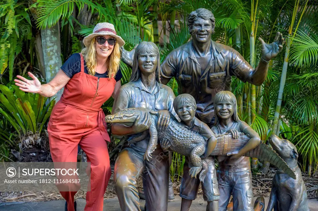 Tourist with statue of Irwin family at the zoo; Beerway, Queensland, Australia