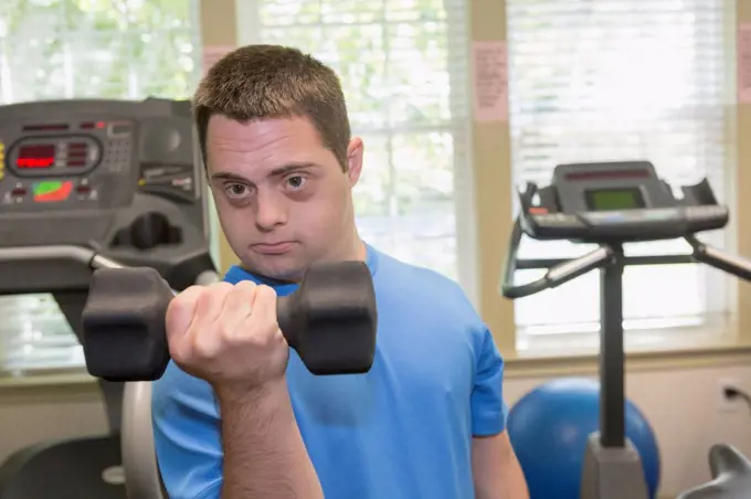 Man with Down Syndrome exercising in a gym with dumbbell