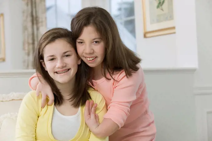 Two teenage girls smiling together, one with birth defect