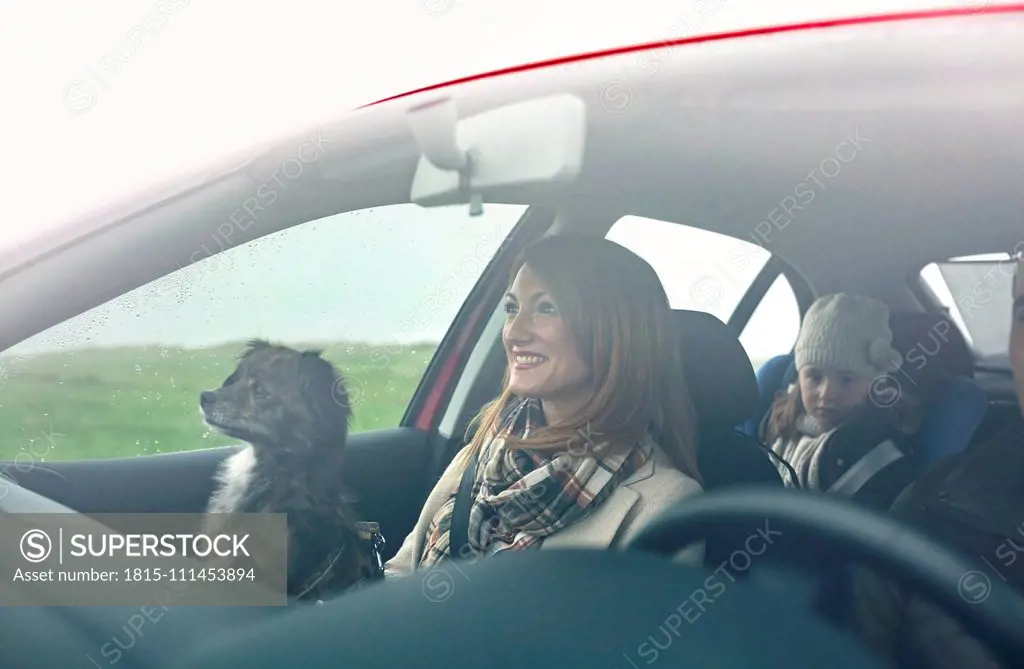 Happy family with small dog in car