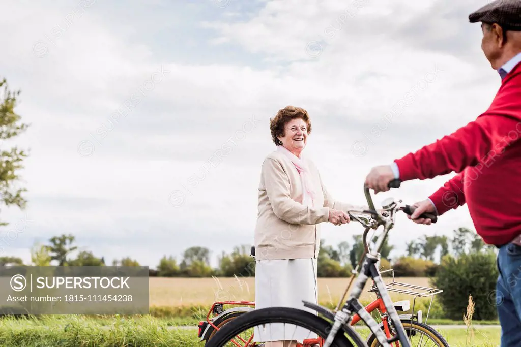 Senior man and woman with bicycles meeting in rural landscape