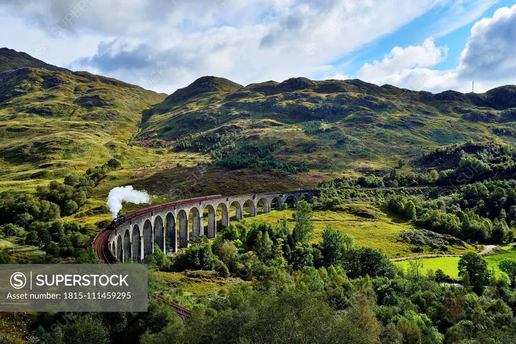 UK, Scotland, Highlands, Glenfinnan viaduct with a steam train passing over it