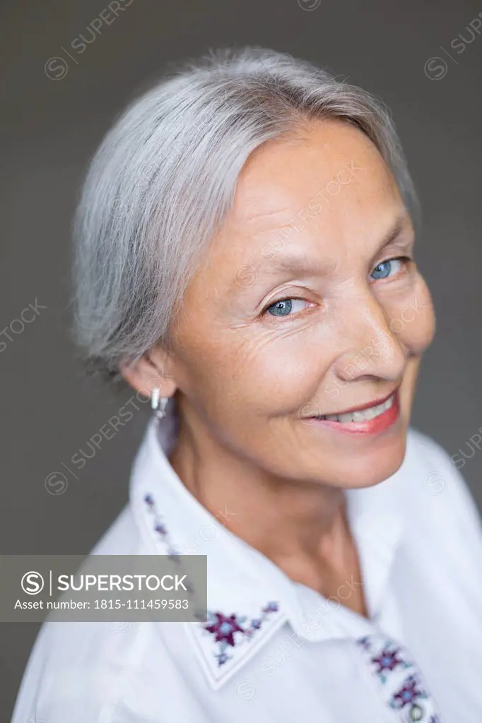 Portrait of smiling enior woman with grey hair and blue eyes