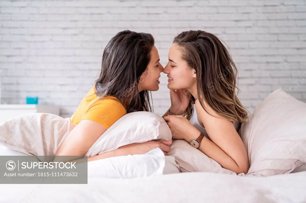 Happy affectionate lesbian couple lying in bed