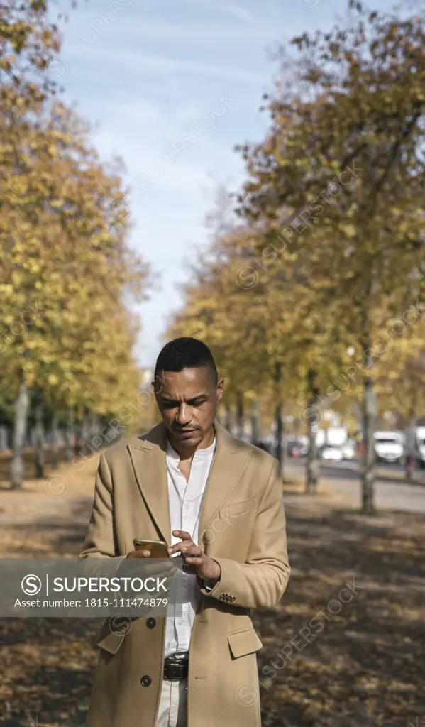 Portrait of businessman using smartphone in autumn