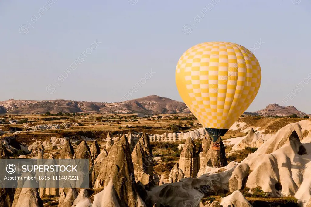 Yellow hot air balloon flying at Goreme National Park, Cappadocia, Turkey