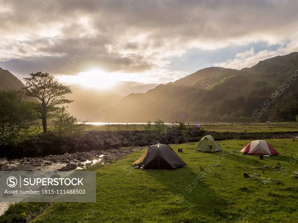 Tents on grassy land against cloudy sky during sunset, Scotland, UK