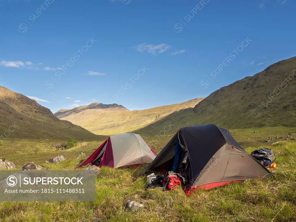 Tents on grassy land against blue sky during sunny day, Scotland, UK