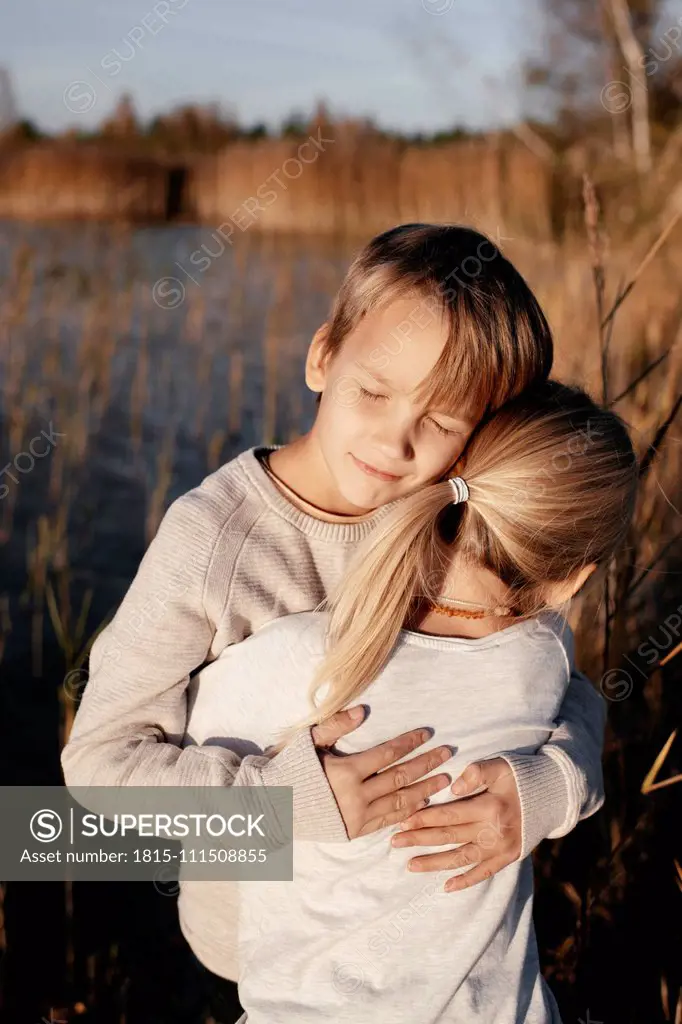 Portrait of boy hugging his little sister in autumnal nature