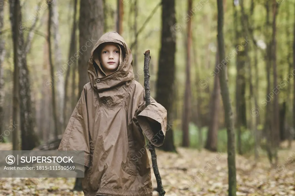 Portrait of boy wearing brown rain coat standing in autumnal forest