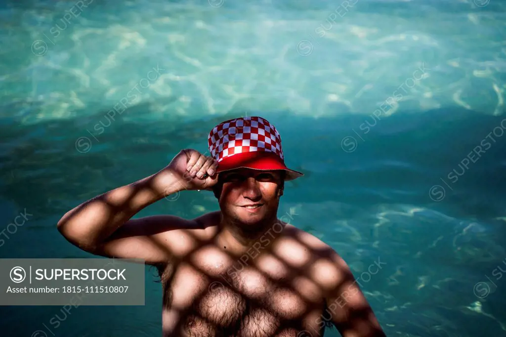 Portrait of overweight man with hat in pool in shady area