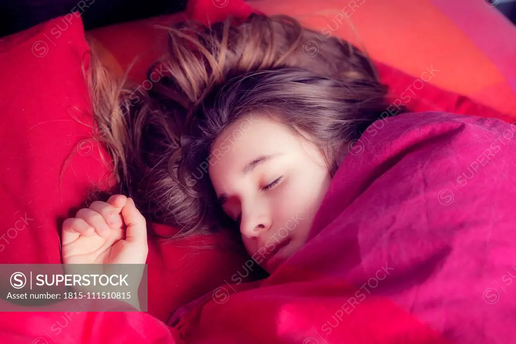 Portrait of girl sleeping in colourful bedding