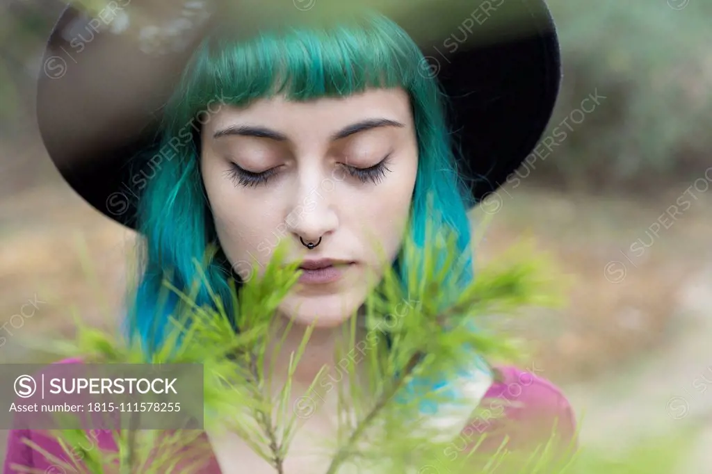 Portrait of young woman with dyed blue and green hair and nose piercing in nature