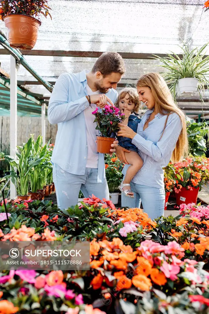 Happy mother, father and daughter buying flowers in a garden center