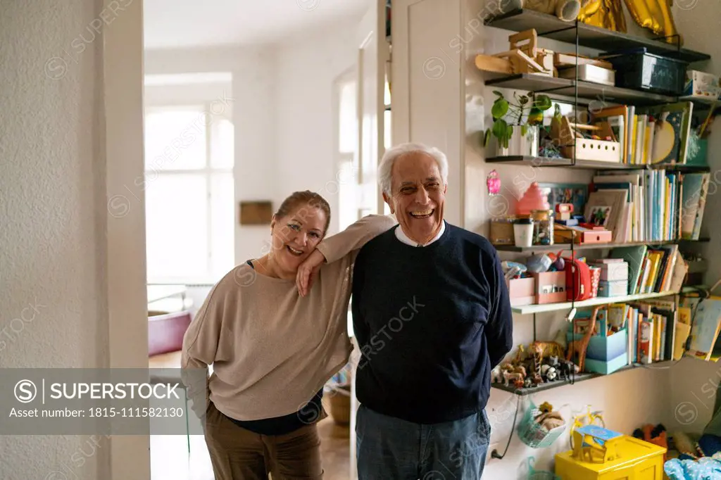 Portrait of happy senior couple standing in children's room