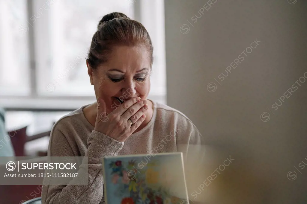 Happy senior woman looking in jewelry box at home