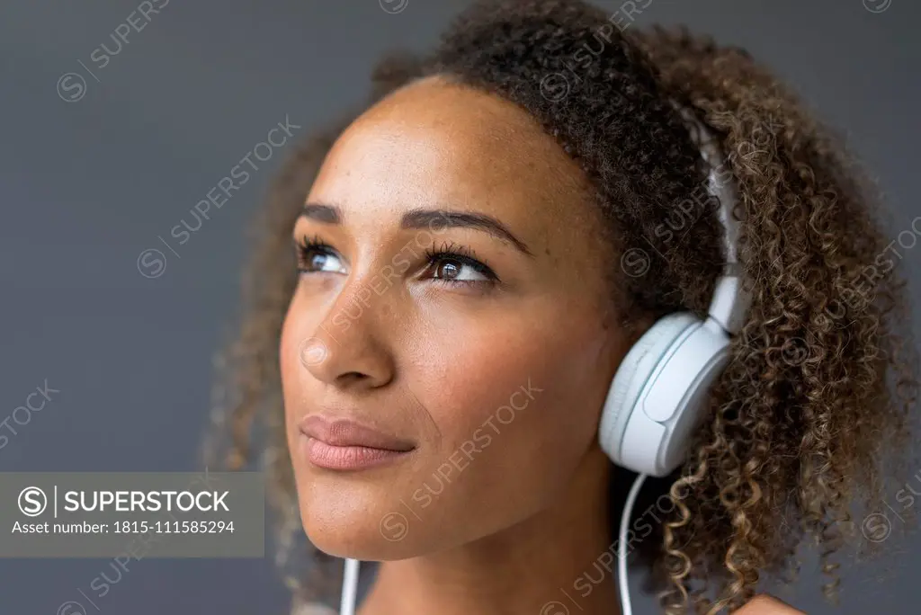 Portrait of young woman with white headphones looking up