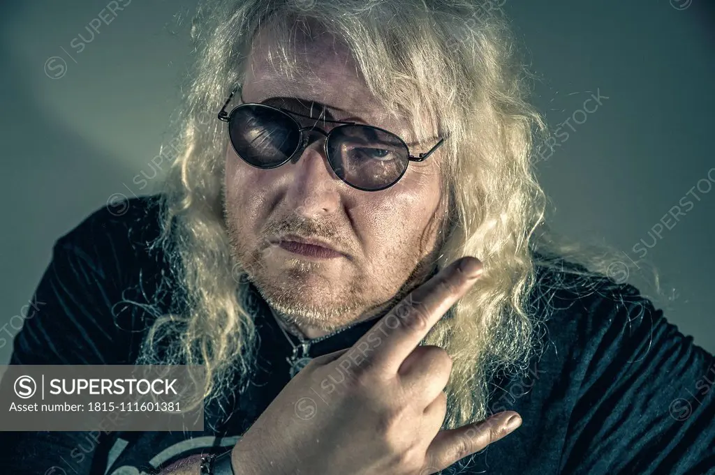 Portrait of blond rocker showing Rock And Roll Sign