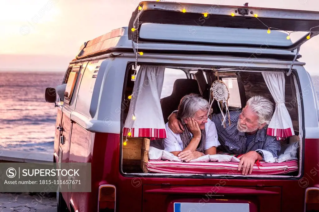 Senior couple traveling in a vintage van, lying in boot