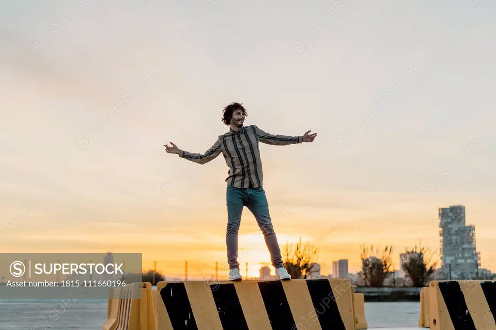 Happy man standing on barrier enjoying sunset, Barcelona, Spain