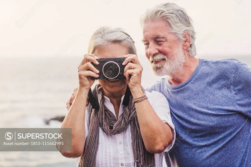 Travelling senior couple, taking pictures at the sea