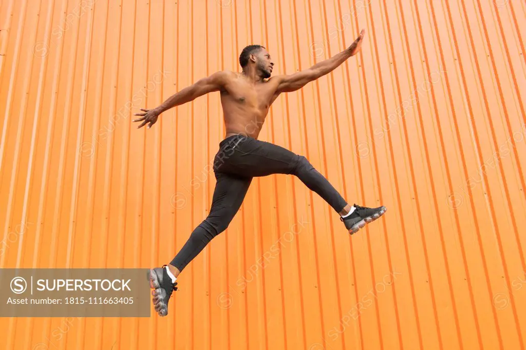 Athlete jumping in front of an orange wall