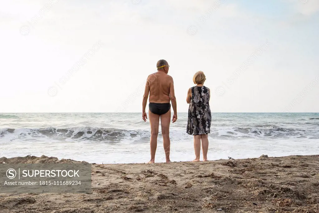 Italy, Sicily, senior couple at the beach looking at the sea