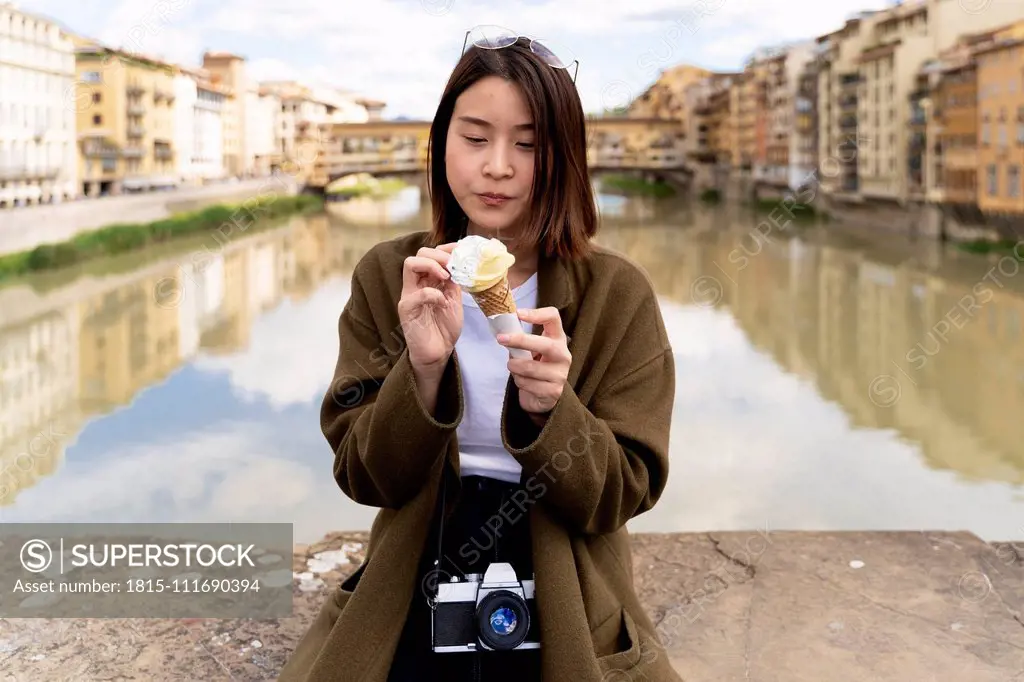 Italy, Florence, young tourist woman eating an ice cream cone at at Ponte Vecchio