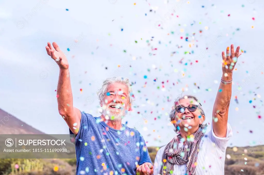 Happy senior couple celebrating with confetti outdoors